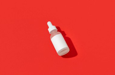 Kırmızı arka planda boş beyaz kozmetik damlatıcı. Noel Sevgililer Günü indirimi konsepti. Şablonu en düşük biçimle yapılandır