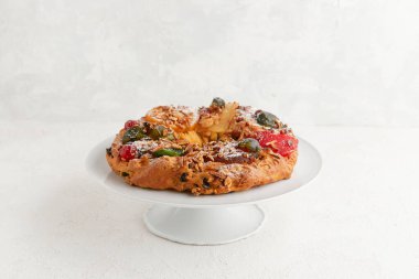 Beyaz kaide üzerinde fındıklı ve şekerli meyveli bir çelenk şeklinde pasta.