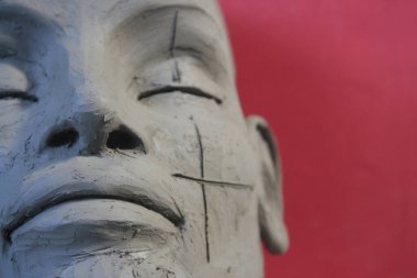 Kırmızı arka planda kilden heykel var. El yapımı portre: modellik, çağdaş sanat, sanat atölyesi.