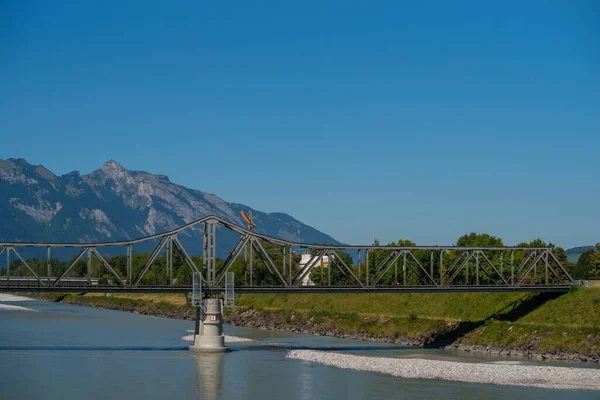 Ren Nehri üzerindeki tarihi demiryolu köprüsü. İsviçre ve Liechtenstein sınırı. Arka planda manzaralı dağ manzarası.