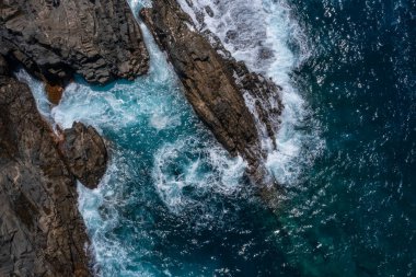 Beautiful landscape with deep blue water. Top view of powerful waves crashing against black volcanic rocks on the coast of Aguas Verdes, Fuerteventura island. Selective focus, blurred background.