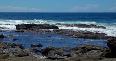 Güçlü dalgalar Fuerteventura adasındaki siyah volkanik kayalara çarpıyor ve köpürüyor. Seyahat ve tatil kavramı.