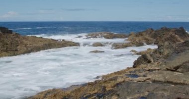 Güçlü dalgalar Fuerteventura adasındaki siyah volkanik kayalara çarpıyor ve köpürüyor. Seyahat ve tatil kavramı.