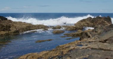 Güçlü dalgalar Fuerteventura adasındaki siyah volkanik kayalara çarpıyor ve köpürüyor. Seyahat ve tatil kavramı.
