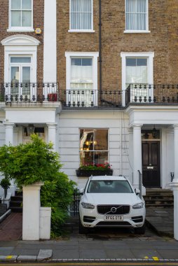 Kensington 'daki Londra şehir merkezindeki tarihi apartmanın önüne park edilmiş parlak beyaz Volvo. Güneşli bir sonbahar günü.