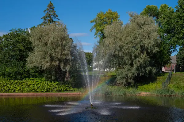 Beautiful landscape - rainbow in a fountain in the middle of the pond in the Valli park the Prnu city centre on a sunny summer day. Parnu, Estonia.
