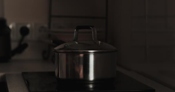 一个年轻女性在厨房的电炉上做饭的特写镜头 女人打开锅盖 用木勺搅拌食物 一位白人家庭主妇在做饭 — 图库视频影像
