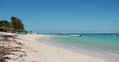 Mauritius 'taki Idyllic Tropikal Plajı, Turkuaz Suları ve Beyaz Kum Cenneti. Palm Trees, Beach Şemsiyeleri ve Kristal Açık Hint Okyanusunda Tekneler ile Sahilde