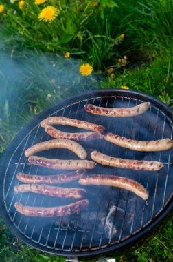 Açık Mangal Izgarası 'nda cızırdayan Sosisler. Smoky Bratwurst Sunny Backyard 'da Kömür Pişiriyor