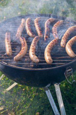 Açık Mangal Izgarası 'nda cızırdayan Sosisler. Smoky Bratwurst Sunny Backyard 'da Kömür Pişiriyor