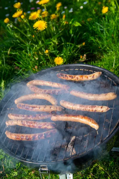 Açık Mangal Izgarası 'nda cızırdayan Sosisler. Smoky Bratwurst Sunny Backyard 'da Kömür Pişiriyor