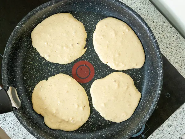 Protein krepleri yapışmaz tavada pişiyor. Benekli Tava 'da Sağlıklı Kahvaltı Yapılıyor. Koyu Granit Mutfak Malzemesinde Dört Yumuşak Vurucu Yuvarlak
