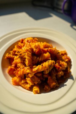 Jambon ve Fusilli, domates soslu. Beyaz tabakta servis edilen tuzlu İtalyan yemeği. Lezzetli Makarna Yemekleri 'nin yakın çekimi.