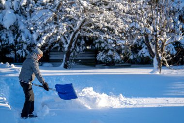 Kış mevsiminde Arka Bahçe Yolu 'ndan Kıdemli Kadın Karı Temizliyor. Kış mevsiminde araziyi karla kaplı ağaçlarla geçindiren yaşlı kişi