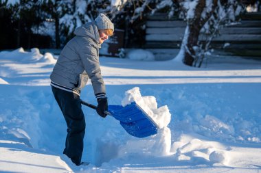 Kış mevsiminde Arka Bahçe Yolu 'ndan Kıdemli Kadın Karı Temizliyor. Kış mevsiminde araziyi karla kaplı ağaçlarla geçindiren yaşlı kişi