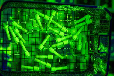 Green Fluorescent Dye on Industrial Fasteners During NDT Testing. Metal Parts in Wire Basket During Penetrant Inspection Process clipart