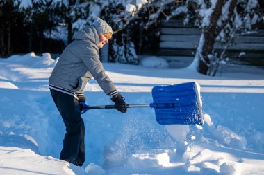 Kış mevsiminde Arka Bahçe Yolu 'ndan Kıdemli Kadın Karı Temizliyor. Kış mevsiminde araziyi karla kaplı ağaçlarla geçindiren yaşlı kişi