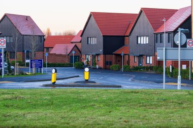 Takeley, UK - December 07, 2024: New modern housing development with contemporary architecture featuring dark cladding and red roof tiles. clipart