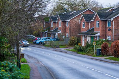 Takeley, Birleşik Krallık - 07 Aralık 2024: Park etmiş arabalı İngiliz mahallesindeki sessiz bir banliyö caddesindeki modern tuğla evler. 