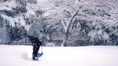 Aktif Kıdemli Kar Temizleme Mavi Kürek ile Güzel Kar Fırtınası sırasında Pet Dog ile. Ağır Kar Altında Bahçesini Koruyan Yaşlı Kadın Kış Sahnesi