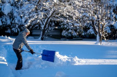 Kış mevsiminde Arka Bahçe Yolu 'ndan Kıdemli Kadın Karı Temizliyor. Kış mevsiminde araziyi karla kaplı ağaçlarla geçindiren yaşlı kişi
