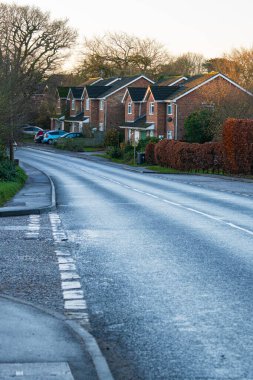 Takeley, Birleşik Krallık - 07 Aralık 2024: Park etmiş arabalı İngiliz mahallesindeki sessiz bir banliyö caddesindeki modern tuğla evler. 