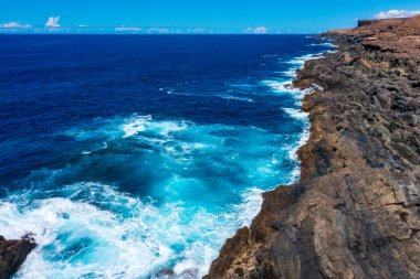 Fuerteventura 'nın çarpıcı kıyı manzarası. Karanlık Volkanik Uçurumlara Karşı Kırılan Turkuaz Dalgalar. Kanarya Adalarından Dramatik Okyanus Manzarası