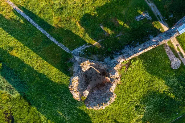 Laiuse Kalesi 'nin havadan görünüşü canlı yeşil çimlerle çevrili antik taş temelleri gösteriyor. Bu tepeden tırnağa İHA perspektifi, ortaçağ Estonya kalesinin tarihsel planını gözler önüne seriyor.