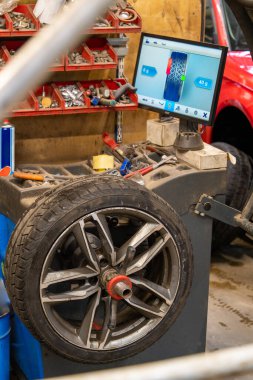 Mevsimsel Lastik Değişikliği sırasında Otomotiv Atölyesinde Dijital İzleyici ile Modern Tekerlek Dengeleme Ekipmanı. Elektronik Ağırlık Dağıtım Analizi ile Profesyonel Dengeleyicide Tekerlek Bağlandı