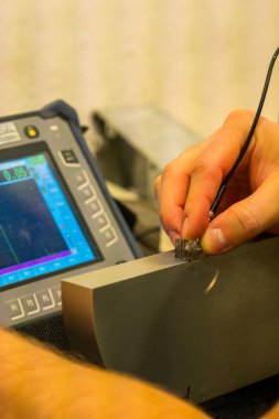 NDT Laboratuvarındaki Referans Bloğunda Ultrasonik Test Kalibrasyon Süreci. UT dönüştürücü ayarlarını hassas teftiş için ayarlayan teknisyenlere yakın çekim