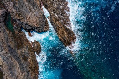 Turkuaz dalgalar Fuerteventura 'nın volkanik kıyı şeridiyle çarpışıyor. Drone fotoğrafçılığı kristal berrak gök mavisi sular ve karanlık kayalık kıyılar arasındaki büyüleyici zıtlığı ortaya çıkarıyor.