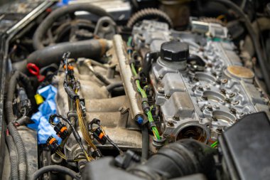 Profesyonel otomotiv tamiri sırasında kapakçığı çıkarılmış modern araba motorunun yakın çekimi. Araç bakımında silindir başı, yakıt enjektörleri ve elektrik konnektörlerinin görüntüsü