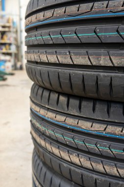 Otomobil tamirhanesinde yepyeni lastik lastikleri ve kaliteli lastik desenleri var. Garaj atölyesine istiflenmiş performans arabası lastiklerinin yakın çekimlerinde ayrıntılı kauçuk bileşiği ve yiv dizaynı ortaya çıkıyor.