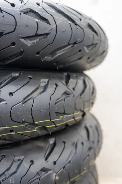 Spor lastik desenli ve hassas mühendislik detaylarına sahip motorsiklet lastiklerinin yakın çekimi. Yeni siyah motosiklet lastiği gelişmiş kavrama teknolojisi ve performans odaklı yiv tasarımı sergiliyor