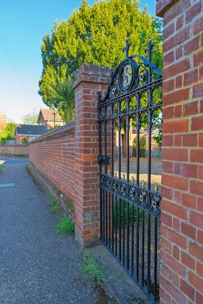 Norwich caddesi İngiltere 'de kırmızı tuğlalı duvara işlenmiş Victoria tarzı süslü demir kapı. Dekoratif Black Metal giriş kapısı geleneksel İngiliz mimari işçiliğini gösteriyor