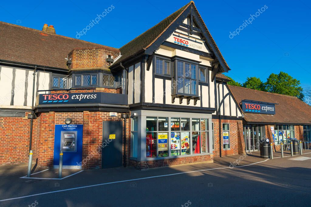 Norwich, UK- May 17, 2025: Tesco Express convenience store in a traditional Tudor-style building in Norwich, UK. Modern retail chain occupying historic architecture with an ATM and parking area