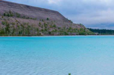 Turkuaz göl dramatik kireçtaşı uçurumları ve huş ağaçlarıyla çevrili. Bulutlu bir gökyüzünü yansıtan kristal berrak suyla el değmemiş kuzey doğası.