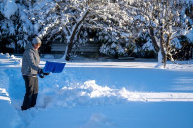 Bir asistan olarak kış bakım çalışmaları yoğun kar birikimini arazi yolundan kaldırır. Karlı ağaçlar ve bir yerleşim bölgesi. Mevsimsel hava temizliği..