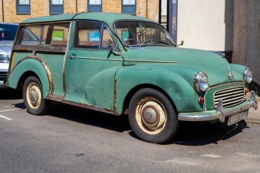 Norwich, UK- 17 Mayıs 2025: Klasik yeşil Morris Minor Traveller arazi arabası Norwich, İngiltere caddesinde park edilmiş ahşap süslemeli. 1950 'lerin klasik İngiliz otomobili yıpranmış patinaj ve pas gösteriyor.