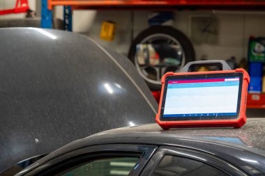 Automotive Diagnostic Tablet Computer in a Professional Auto Repair Workshop. Mechanic Digital Tool for Vehicle Testing and Analysis