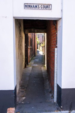 Norwich, UK- 17 Mayıs 2025: Norwich, İngiltere 'de Ninhams Court yazılı geleneksel İngiliz sokağı girişi. Norfolk 'taki tarihi binalar arasındaki dar tuğla koridor.