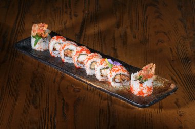 Yüksek açılı Japon uramaki seti, tobiko balığı yumurtası ve ahşap masa üzerinde kızarmış yengeç pençeleri.