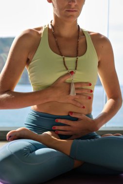 Güneşli bir günde terasta yoga yaparken Lotus 'ta oturan ve nefes alan tanınmamış sakin bir kadın.