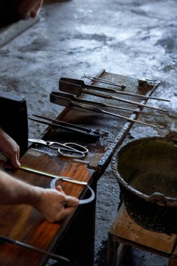 Sanayi atölyesindeki ahşap tezgahta cam yapan yüksek açılı bir fabrika işçisi.