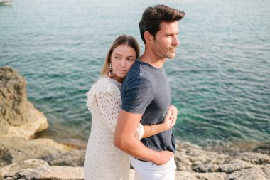 Yaz tatili boyunca kayalık kıyılarda sevgilisinin sarılışının yan görüntüsü.