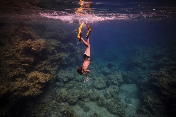 サンゴ礁の近くの海の水中で泳ぐスリッパとマスクで認識できない男性ダイバーのサイドビュー — ストック写真