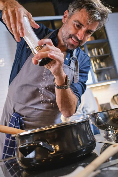 Chef Barbudo Delantal Parado Estufa Agregando Condimento Plato Mientras Cocina — Foto de Stock