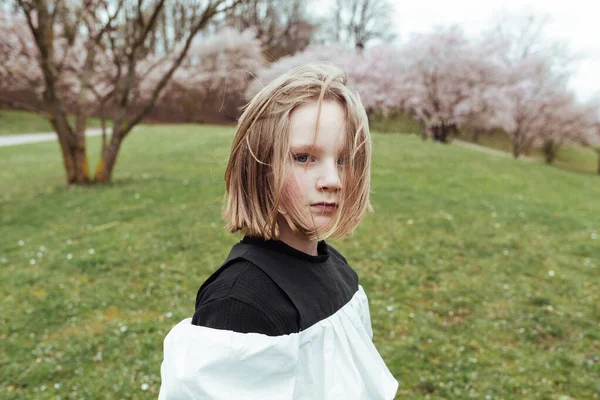 从上面的肖像画上 是一个严肃的少女 站在盛开的樱桃附近的公园里 — 图库照片