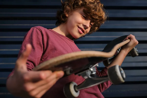 Знизу Позитивний Маленький Фігурист Посміхається Перевіряє Скейтборд Стоячи Біля Темно — стокове фото