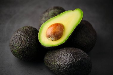 Stock photo of fresh green organic avocados isolated on black background. clipart